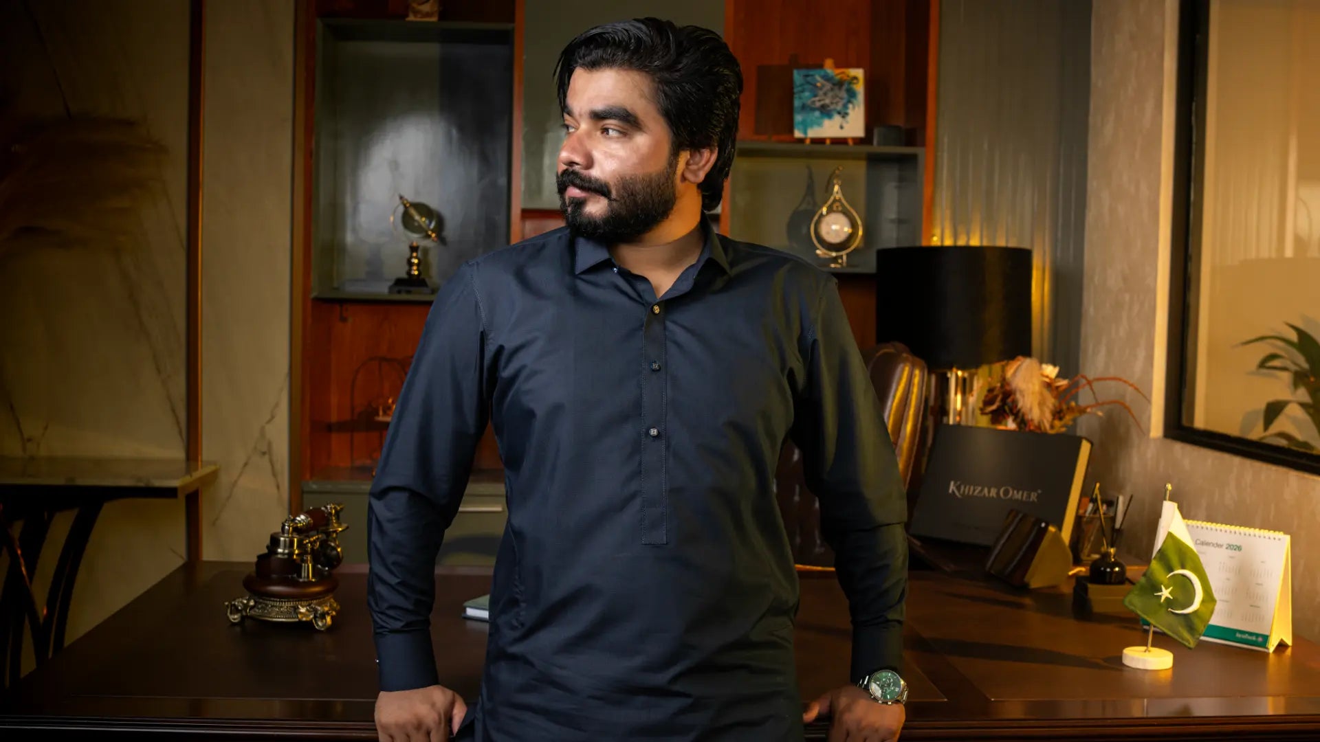 Khizar Omer in a navy kameez standing at his office desk